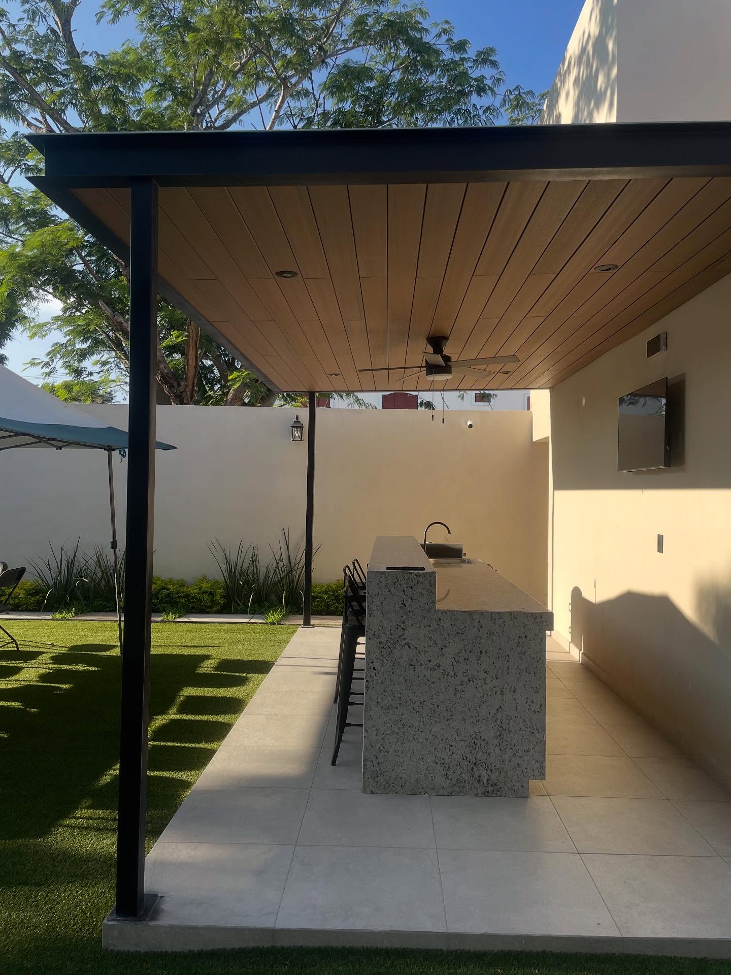 Terraza techada con barra y cocina exterior